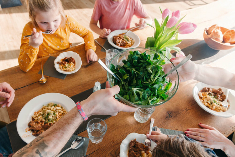 Familie sitzt am gedeckten Tisch und isst | © Land schafft Leben