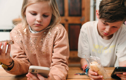 Kinder schauen auf Handy und essen dabei | © Land schafft Leben