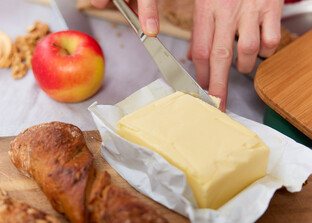 Frau bereitet eine Jause mit Butter, Weckerl Apfel und Nüssen zu | © Land schafft Leben