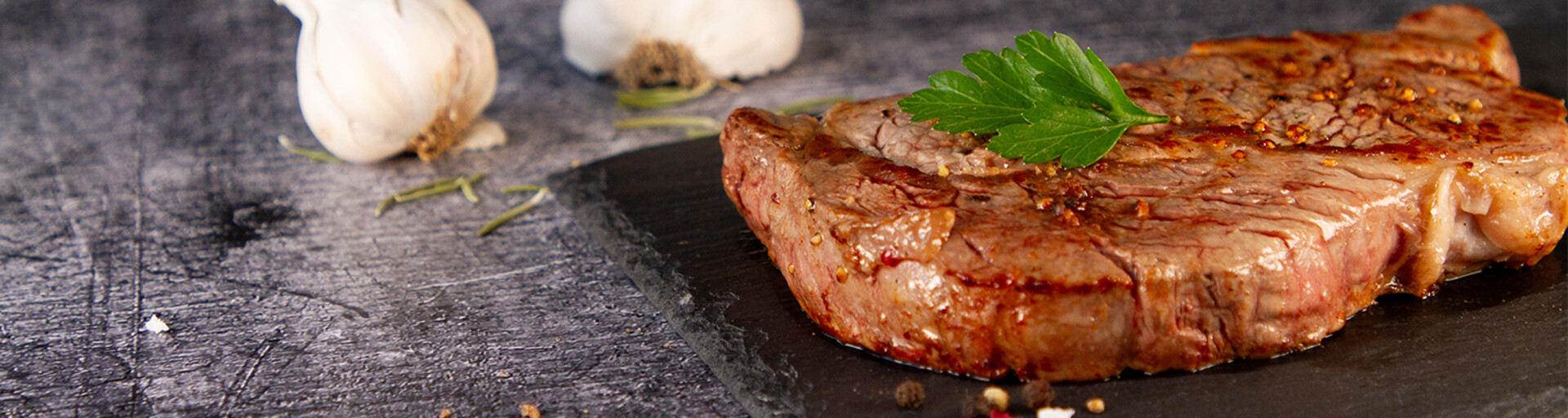 Rindersteak gebraten auf Teller mit Knoblauch und Petersilie | © Land schafft Leben